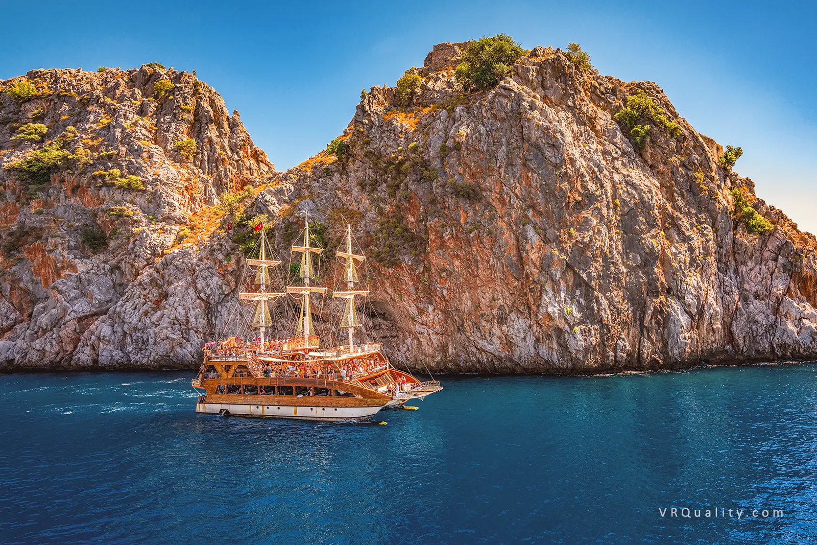 Туристический пиратский корабль у скалистого берега Анталии под ярким солнце