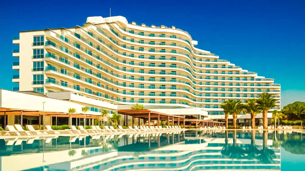 Роскошный пятизвёздочный отель в Дидиме с бассейном и отражением здания в воде под ярким голубым небом.