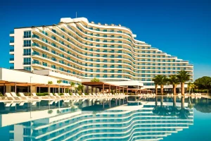 Роскошный пятизвёздочный отель в Дидиме с бассейном и отражением здания в воде под ярким голубым небом.